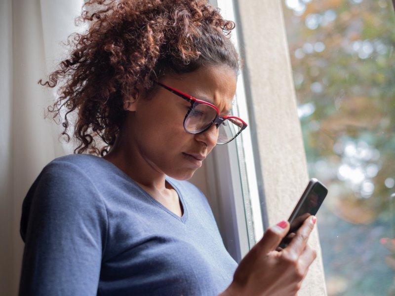 Frau guckt konzentriert auf ihr Handy.