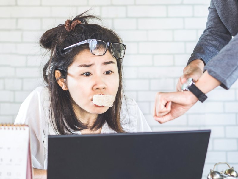 Frau mit Essen im Mund unter Zeitdruck