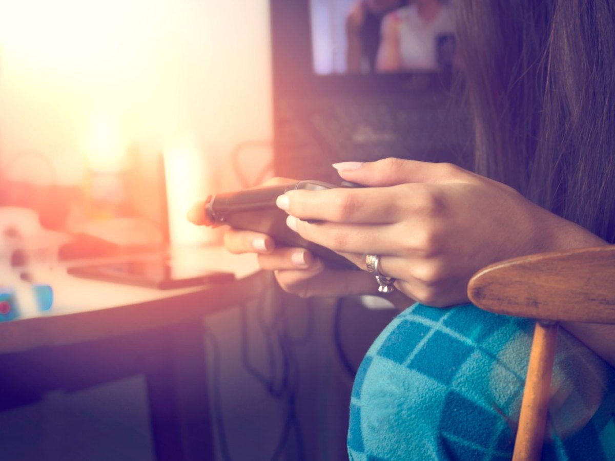 Frau spielt mit Handheld-Konsole.