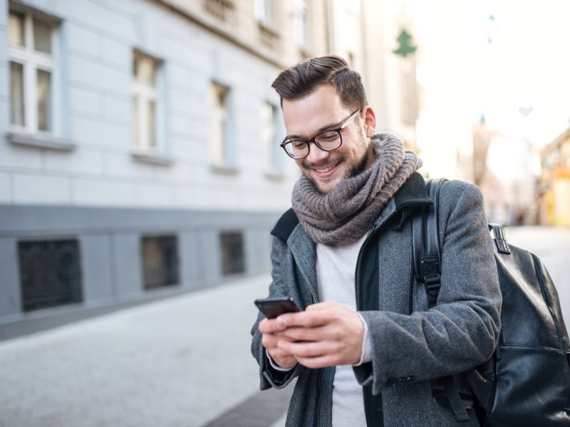 Mann guckt auf der Straße auf sein Handy.