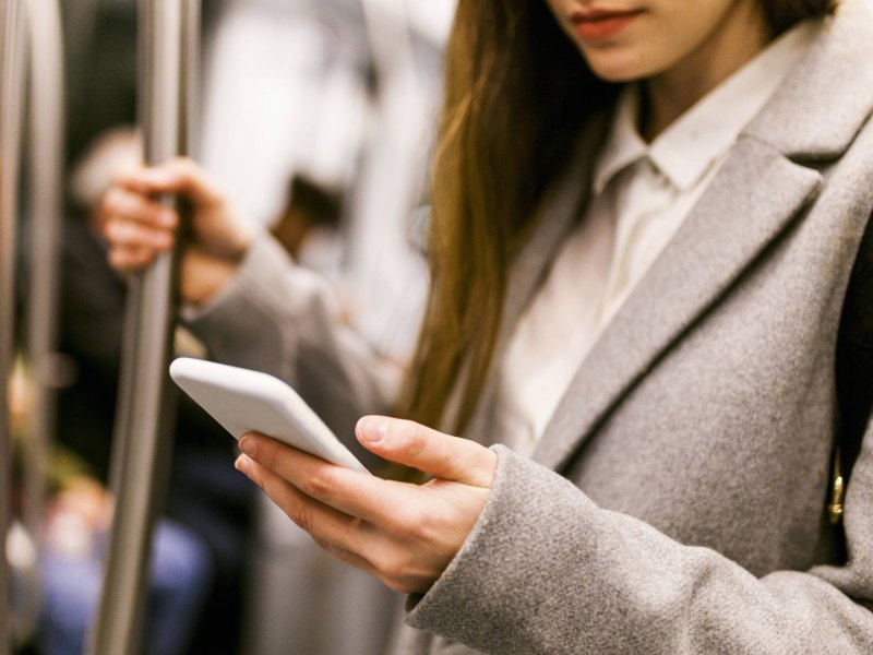 Frau mit einem Handy in der U-Bahn