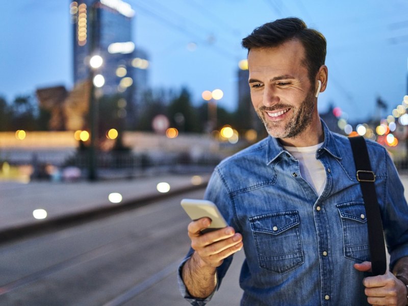 Mann guckt glücklich auf sein Handy