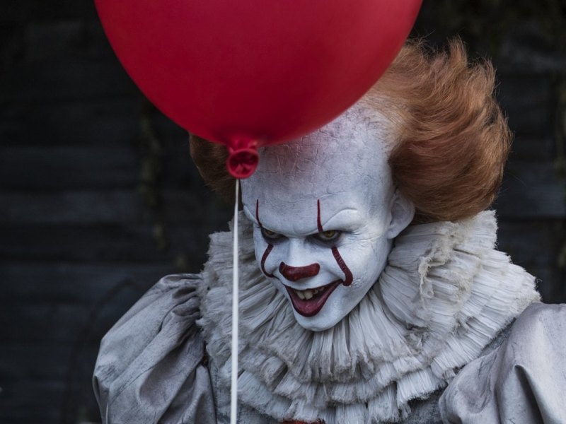 Bill Skarsgård als Pennywise mit einem roten Luftballon.