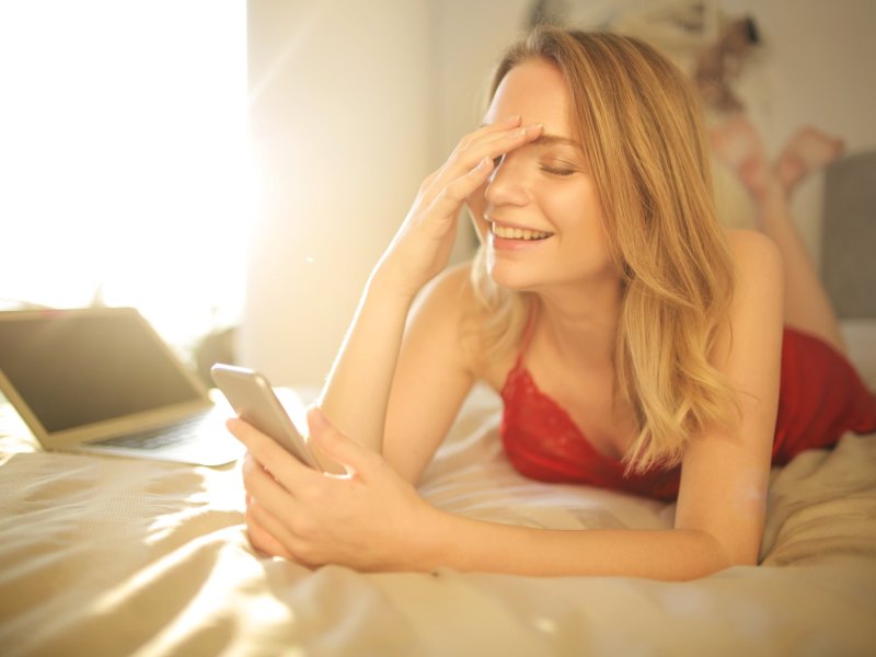 Peinlich berührt blickt eine junge Frau auf ihre Handy.