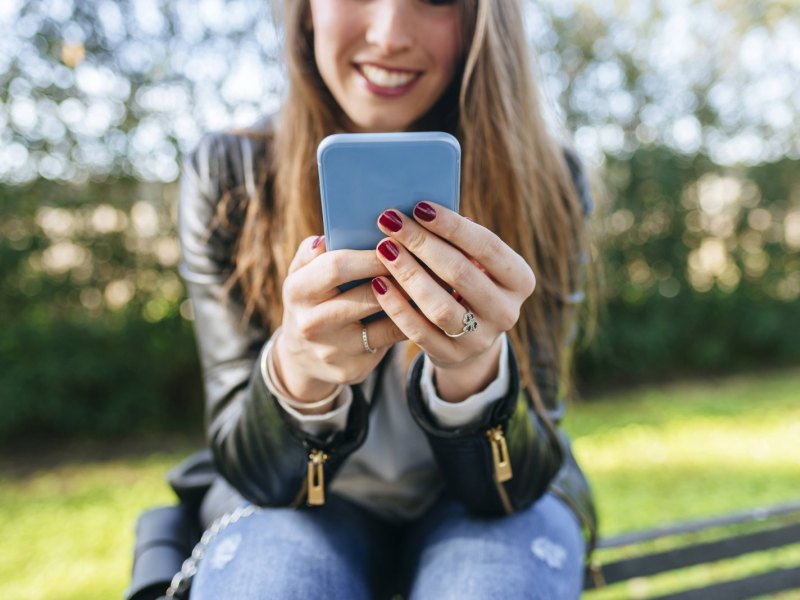 Junge Frau hält iPhone in der Hand.