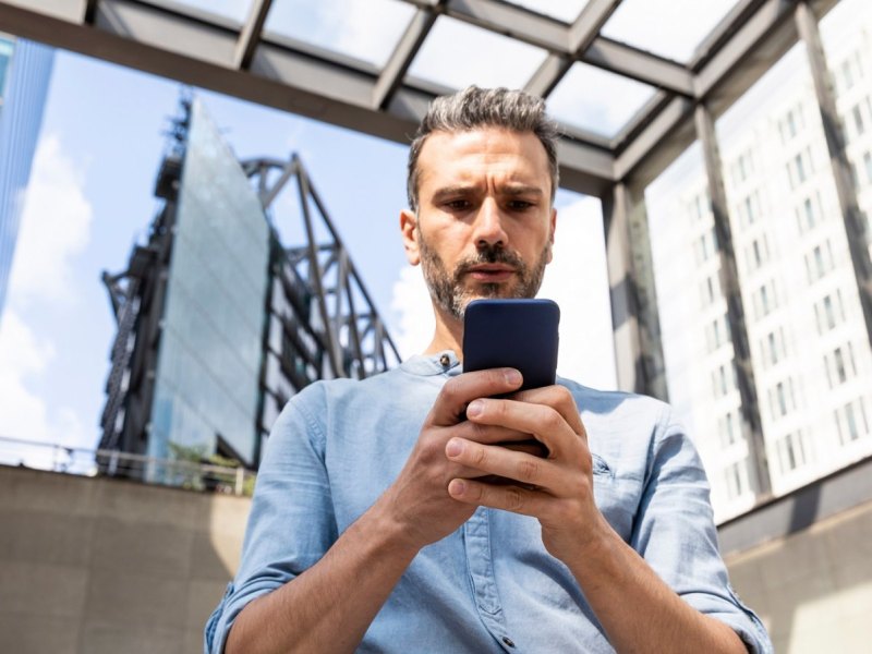 Ein Mann starrt verwundert auf sein Smartphone.