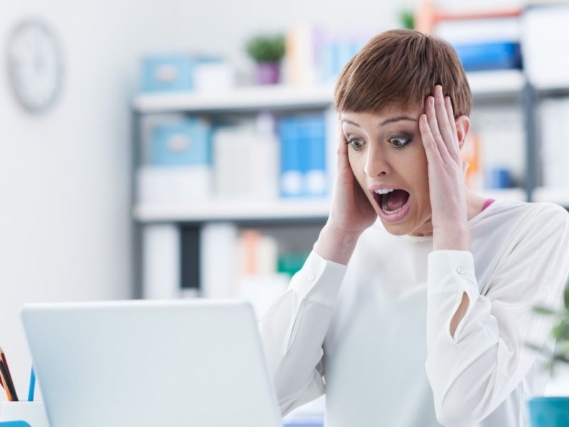 Frau schockiert am Laptop