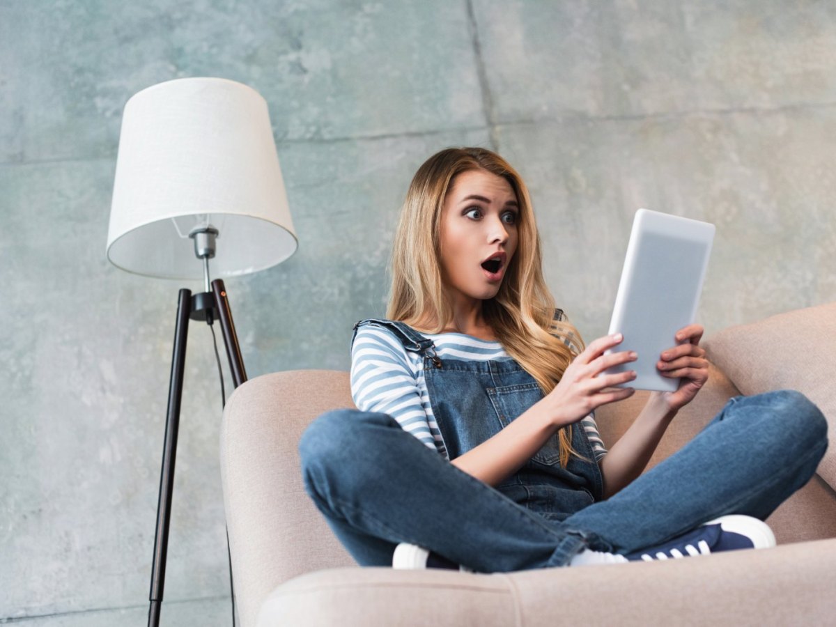 Frau schaut erstaunt auf ein Tablet.