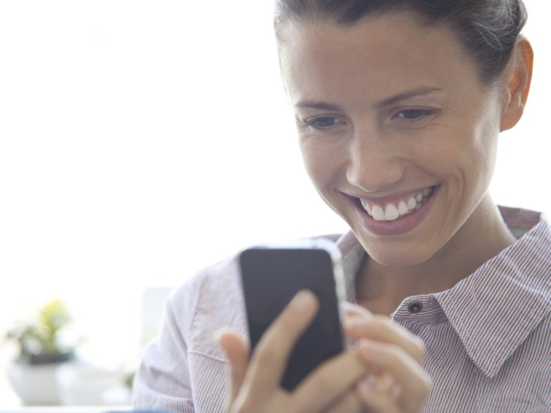 Frau schaut fröhlich aufs Smartphone