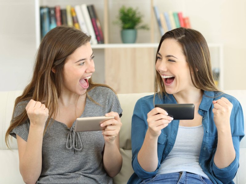 zwei frauen freuen sich über ihre handys