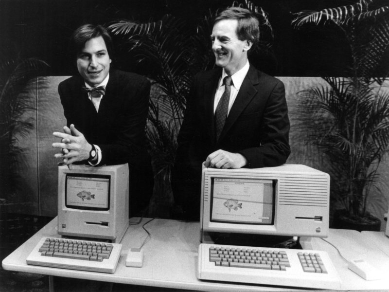 Steve Jobs (links) und John Sculley von Apple stehen hinter zwei Apple-Rechnern