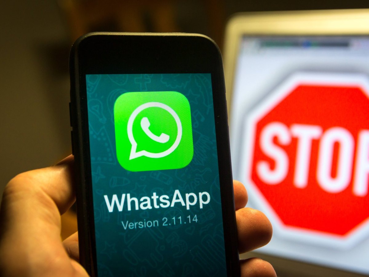 WhatsApp auf dem Handy und ein Stoppschild im Hintergrund