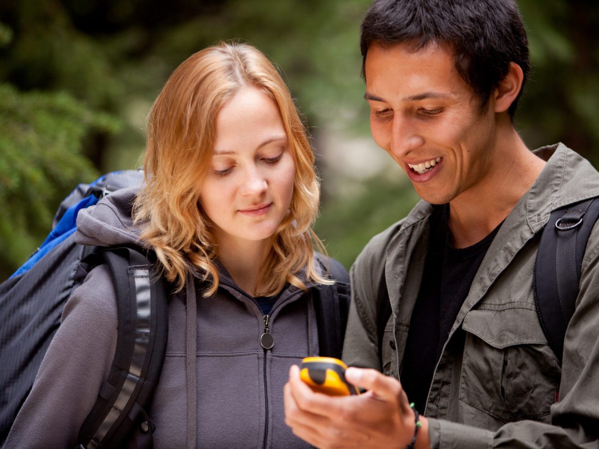 Mann und Frau gucken in Natur auf Handy