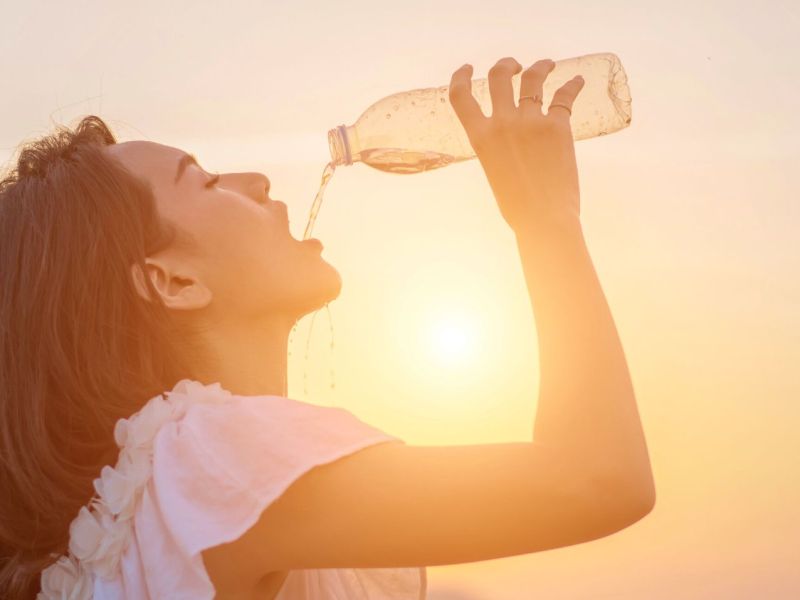 Frau lÃ¤sst Wasser aus einer Flasche in ihren Mund laufen