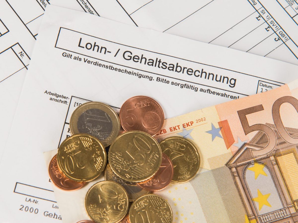 Geld und eine Lohnabrechnung liegen auf einem Tisch.