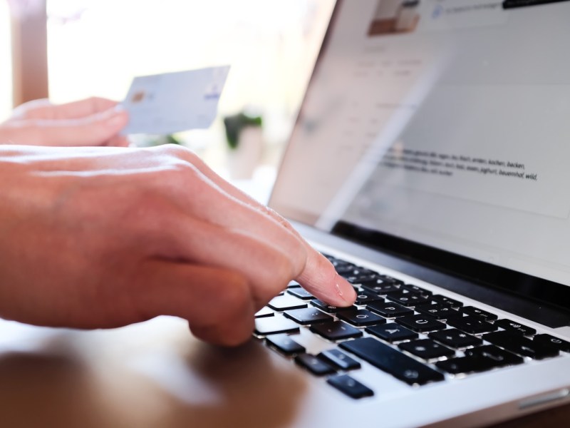 Frau am Laptop hält Kreditkarte in der Hand