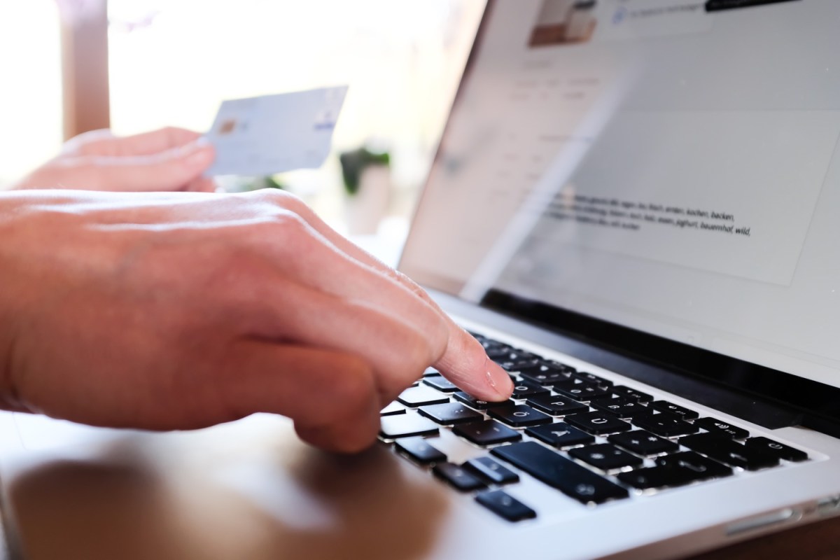 Frau am Laptop hält Kreditkarte in der Hand