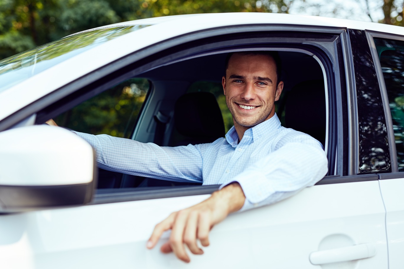 He sell his car. Уверенный молодой на машине. Businessman in the parking near to his car. Man sitting in Front of Window showing his car. New car and man.