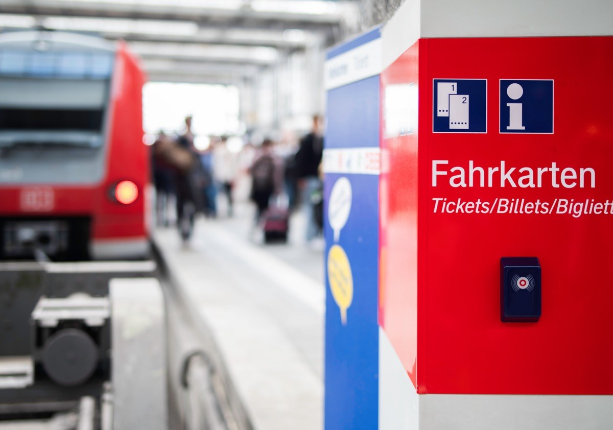 Hinweis auf Tickets am Bahnhof mit Zug im Hintergrund