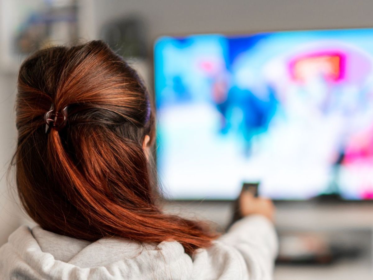 Frau schaut auf einen gebrauchten Fernseher.