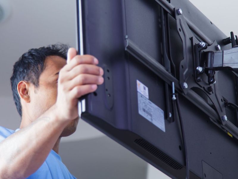 Mann während der Fernseher-Wandmontage.