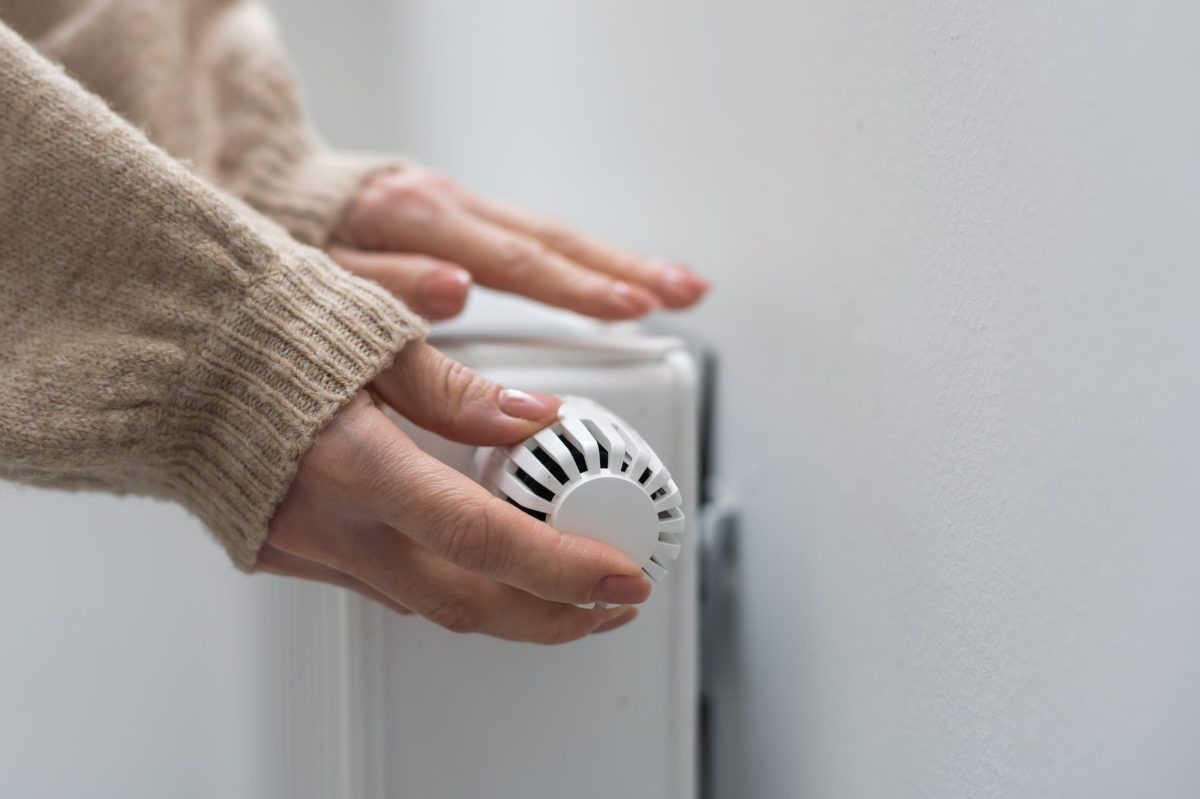 Frau dreht an einer Heizung, die nicht warm wird.