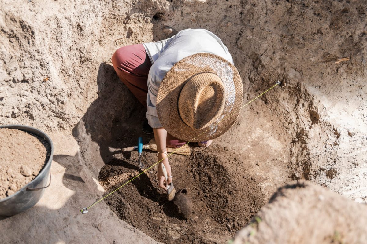 Frau arbeitet mit Werkzeug an einem archäologischen Fund.