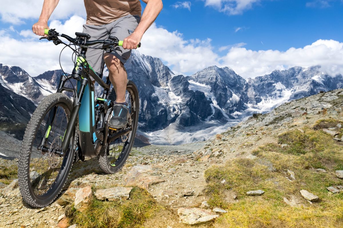 Mann auf einem E-Bike auf einem Bergpfad.