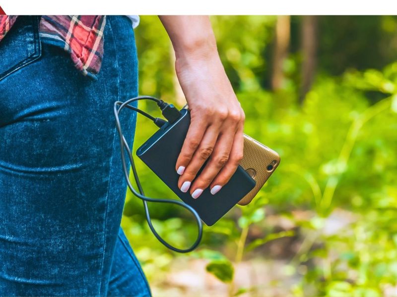 Person läuft mit Powerbank und Smartphone durch einen Wald