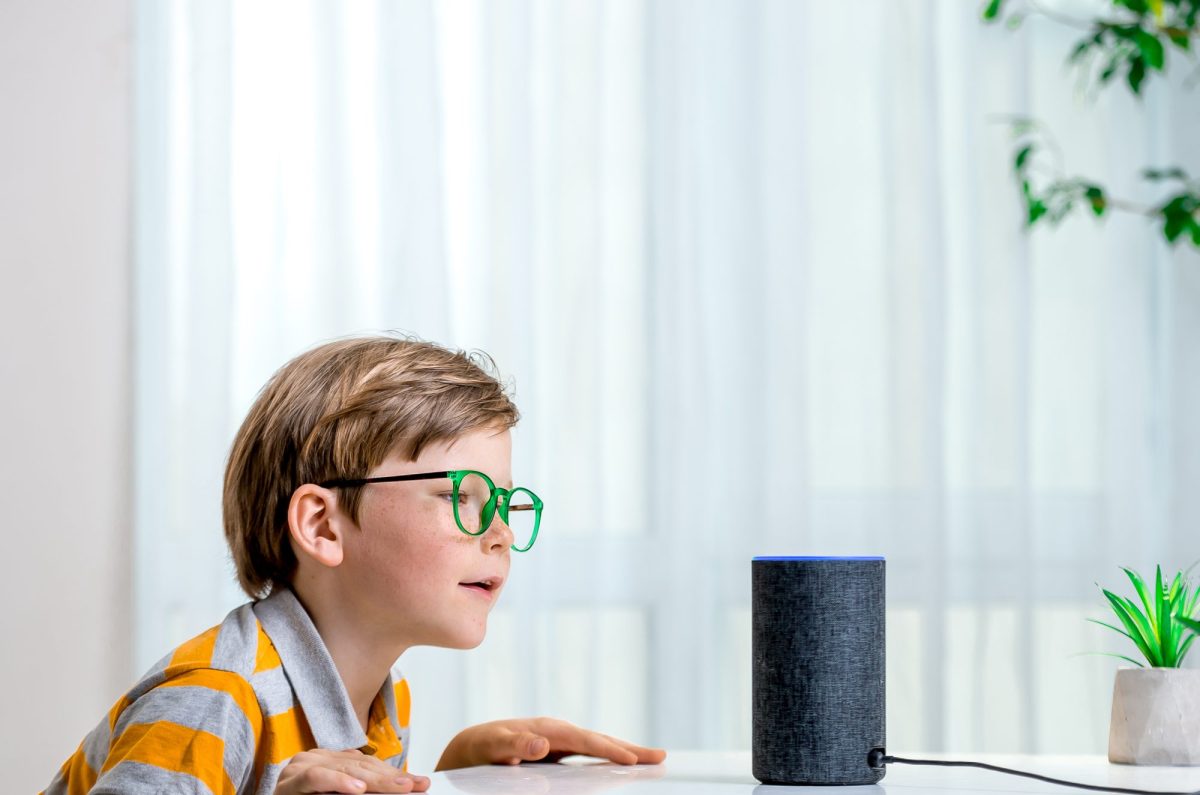 Ein Kind sitzt vor einem Amazon Alexa Lautsprecher.