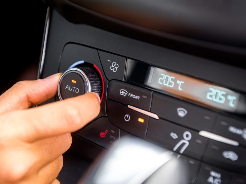 Eine Person bedient den Regler der Klimaanlage im Auto.