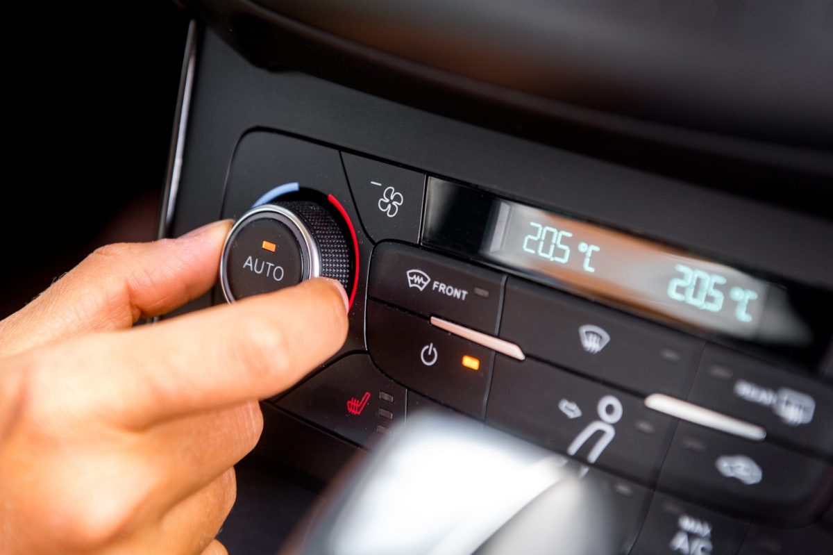 Eine Person bedient den Regler der Klimaanlage im Auto.