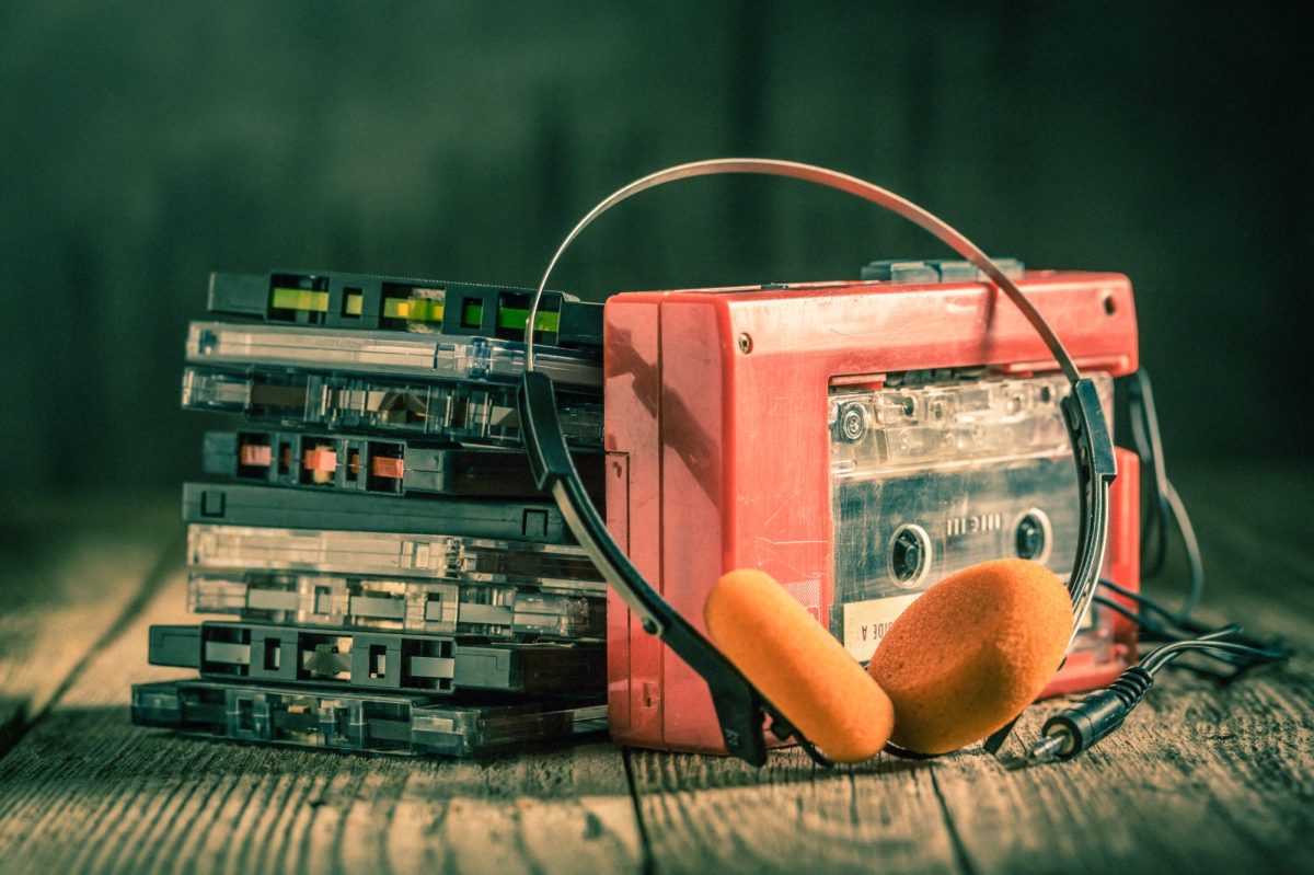 Ein alter Walkman mit Kopfhörern und einem Stapel an Kassetten.