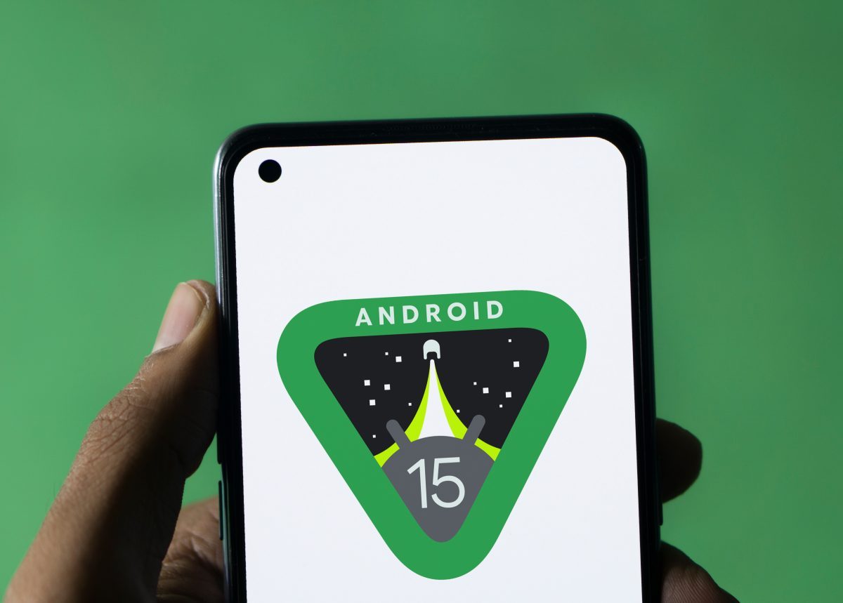 Hand hält Smartphone in der Hand, auf dem Bildschirm ist das Android 15-Logo zu sehen.