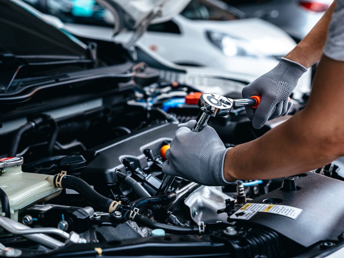 Mann führt Autoreparatur an einem Motor durch.