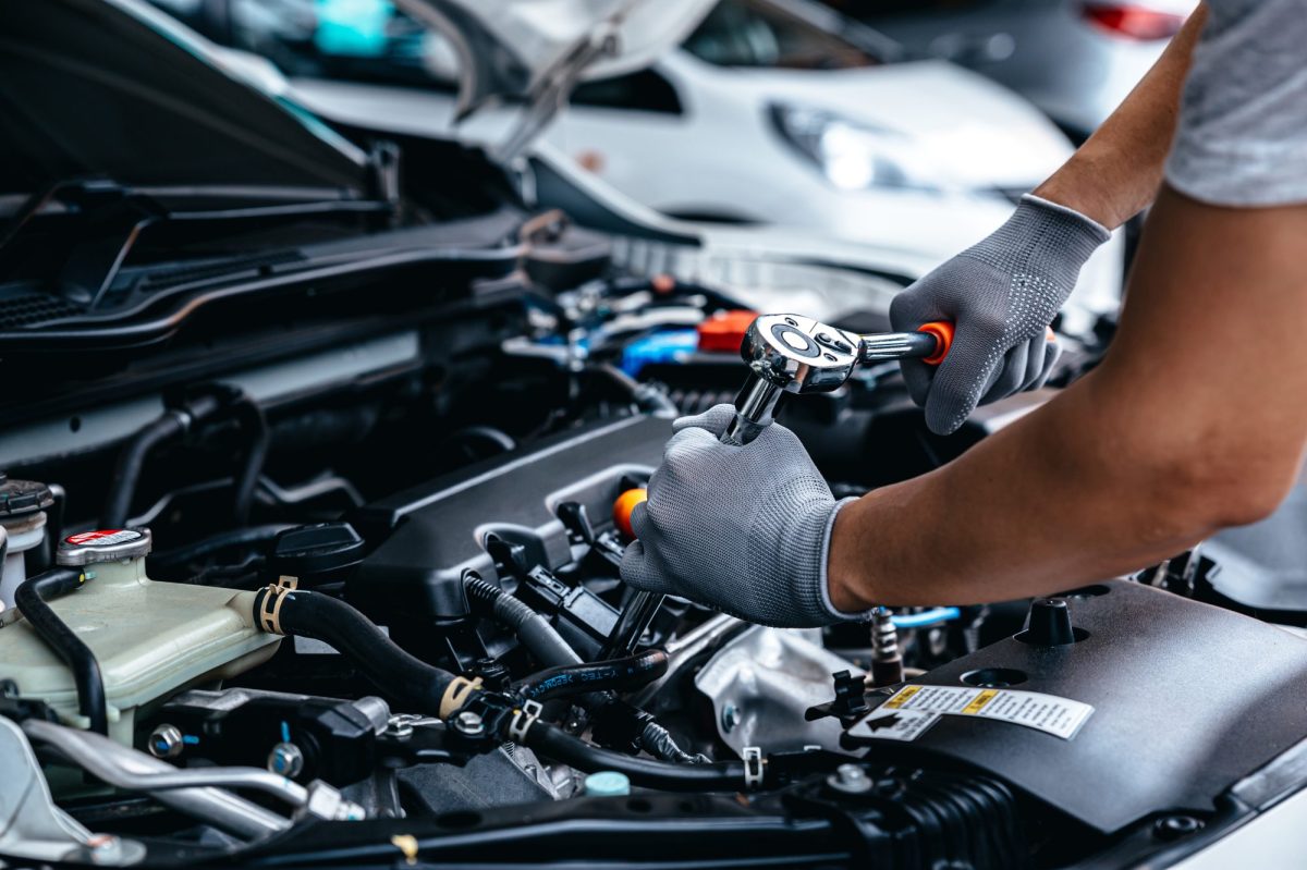 Mann führt Autoreparatur an einem Motor durch.