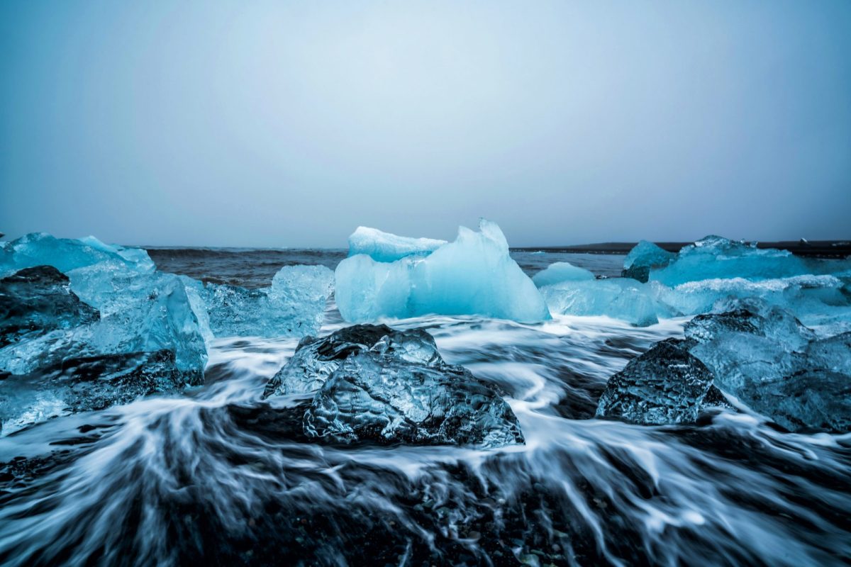 Eisformationen auf dunklem Stein vor einem weißen Himmel.