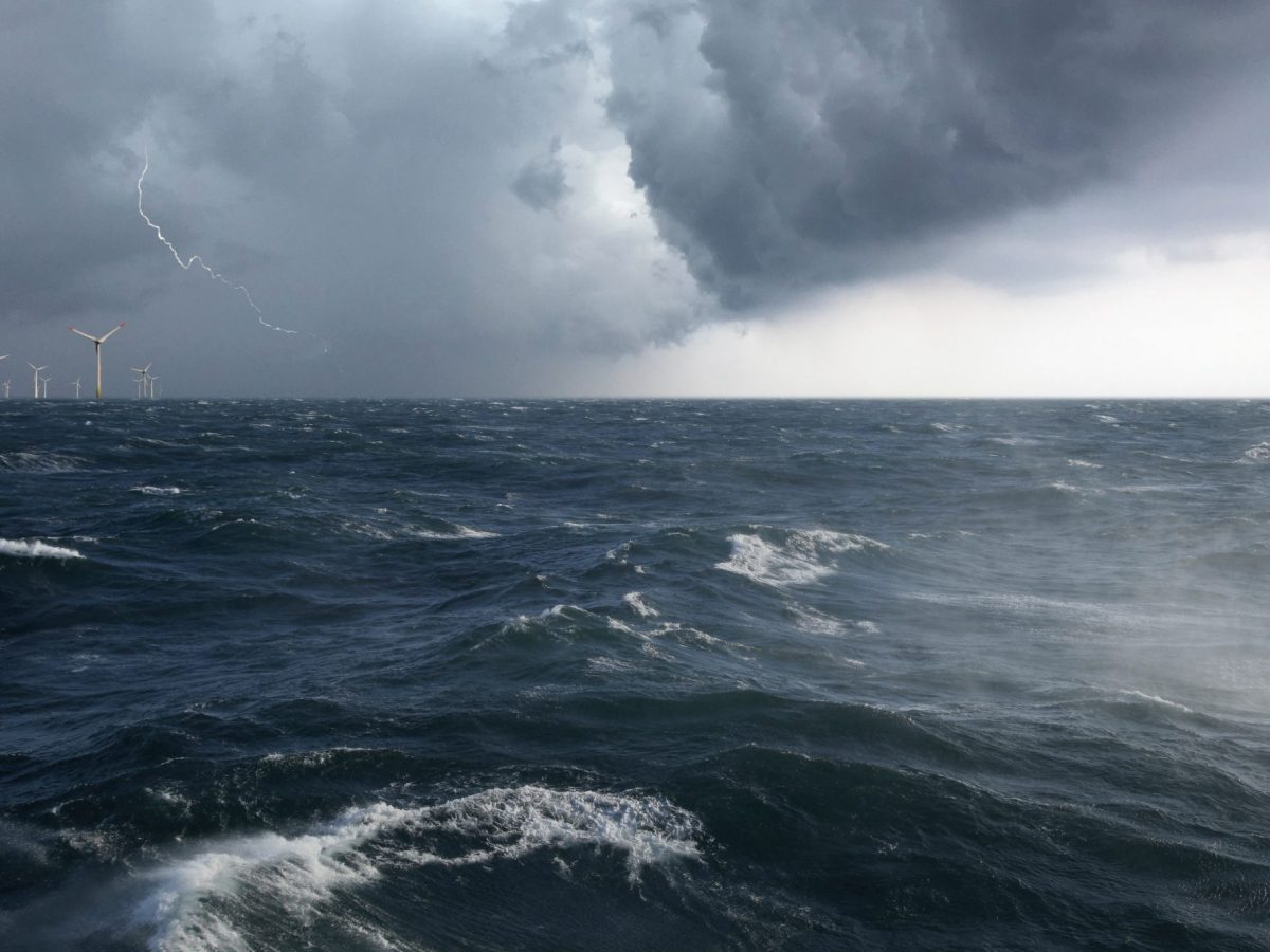 Ein Offshore Windpark mit aufgewÃ¼hlter See in einem Sturm mit Blitz.