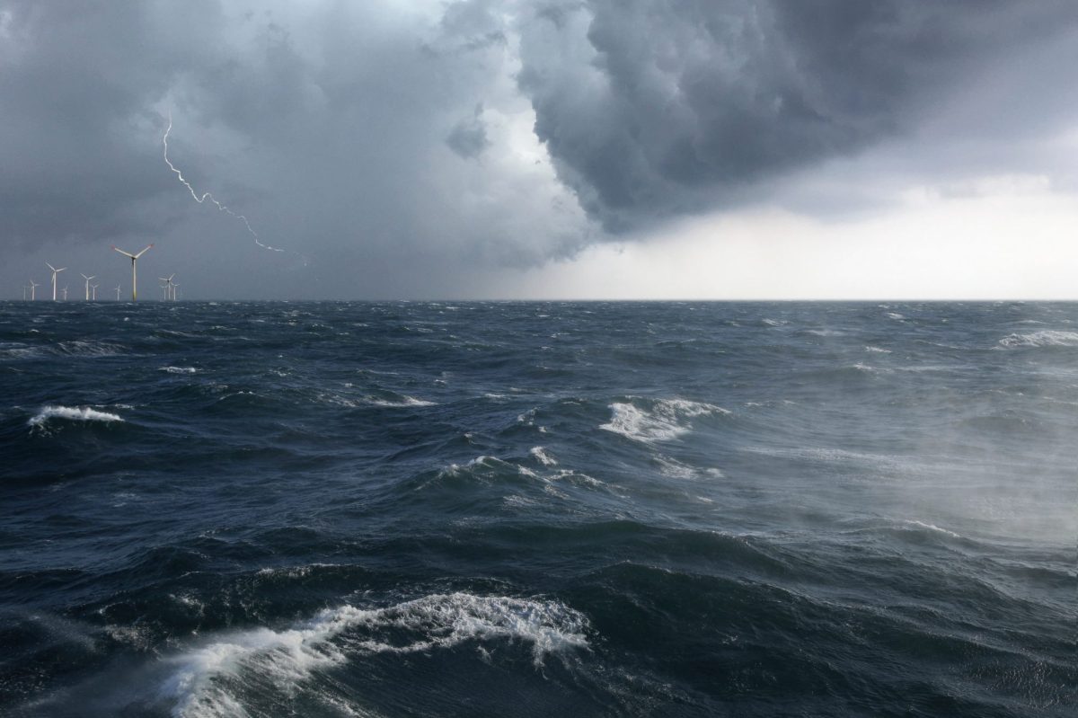 Ein Offshore Windpark mit aufgewÃ¼hlter See in einem Sturm mit Blitz.