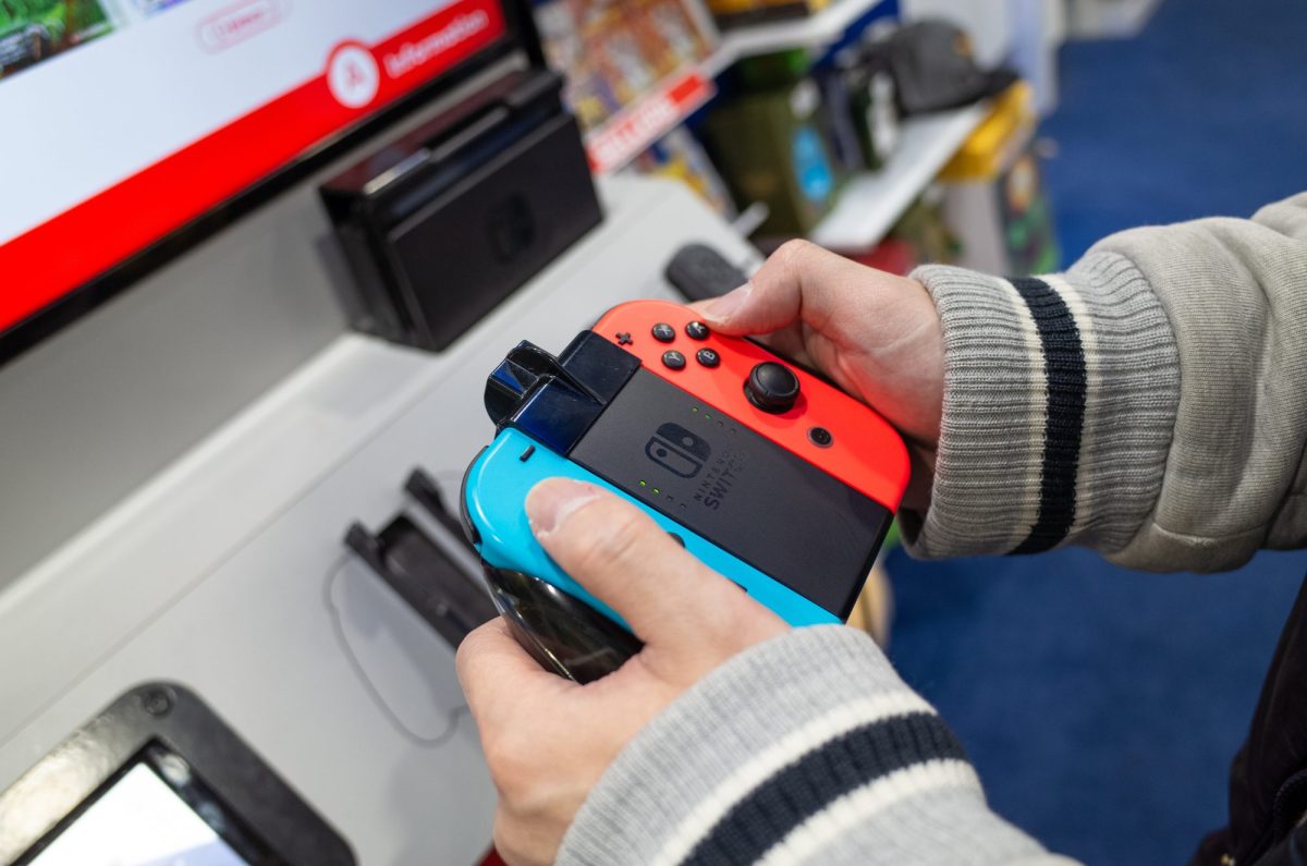 Eine Person hält in einem Laden einen NIntendo Switch-Controller in der Hand.