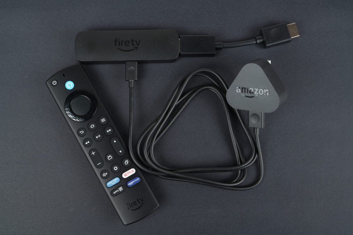 Amazon Fire TV Stick und Fernbedienung liegen auf einem dunklem Untergrund.