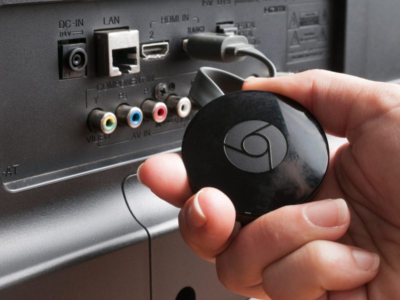 Eine Person schließt einen Chromecast TV-Stick an einen Fernseher an.