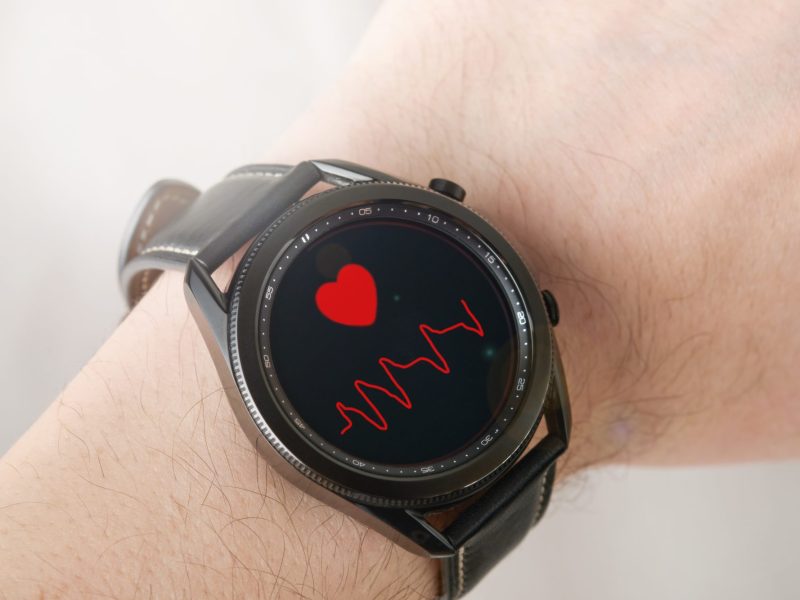 Eine Person trägt eine Samsung Galaxy Watch am Handgelenk, Auf dem Display wird der Puls der Person gemessen.