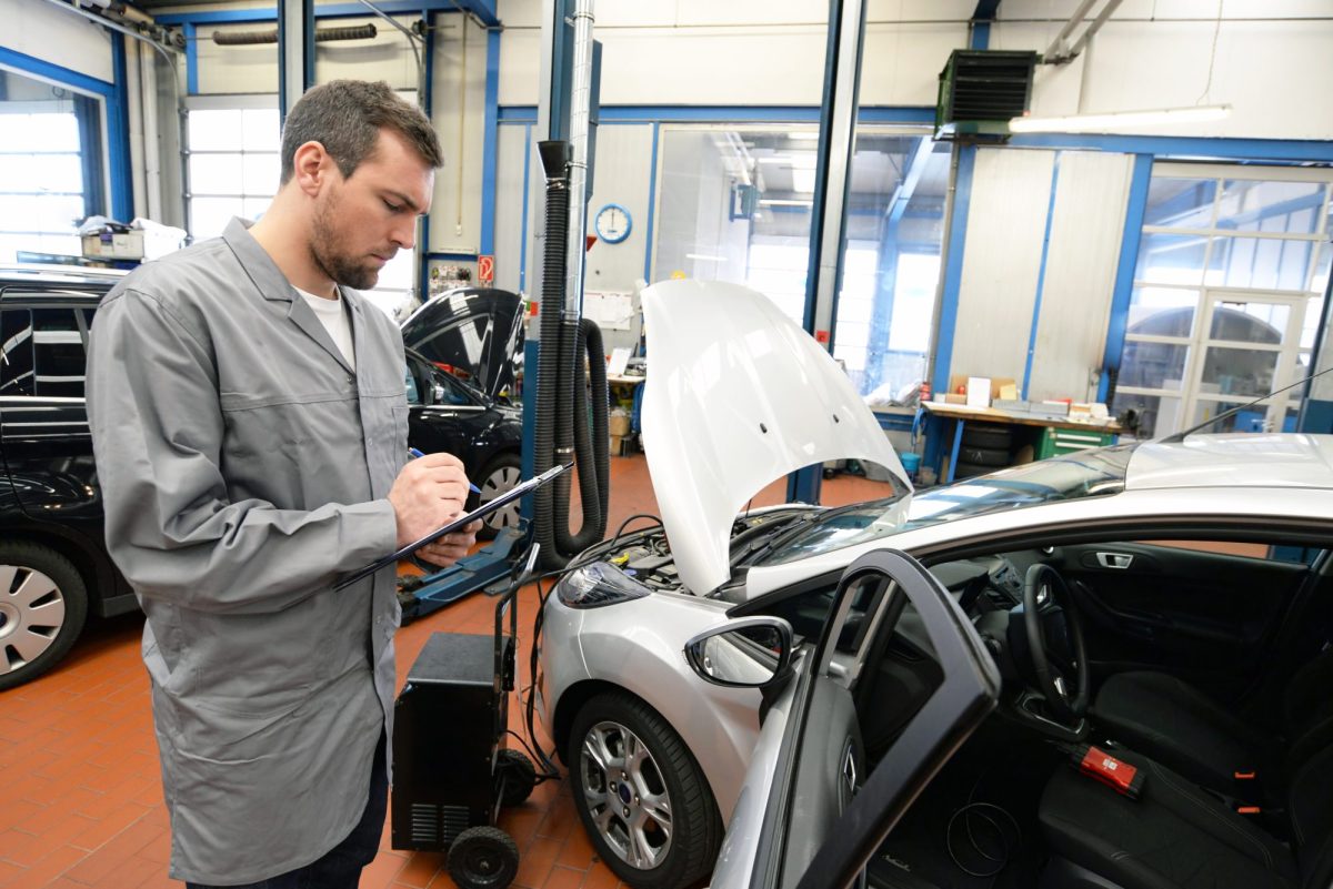 TÜV-Prüfer steht an einem Auto.