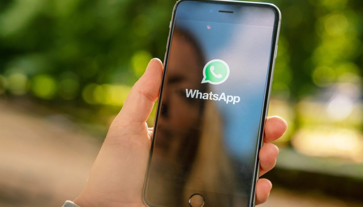 Person hält Handy hoch, das WhatsApp-Startbildschirm zeigt.