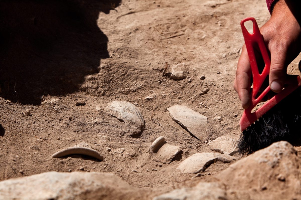 Hände arbeiten an einem archäologischen Fund.