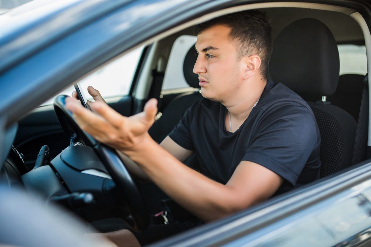 Autofahrer sitzt im Auto und macht eine ungläubige Geste.