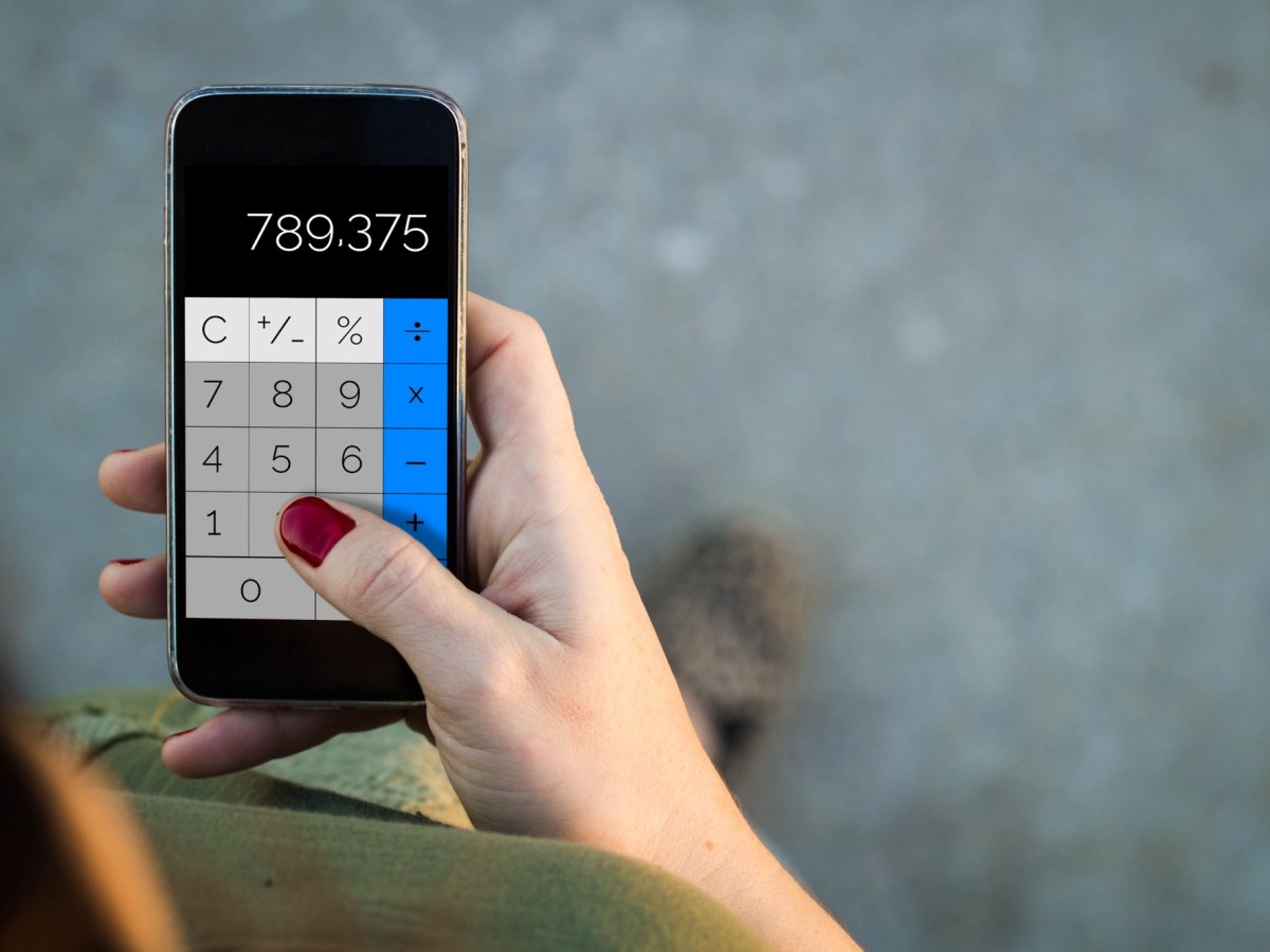 Frau nutzt eine Taschenrechner-App auf dem Handy.