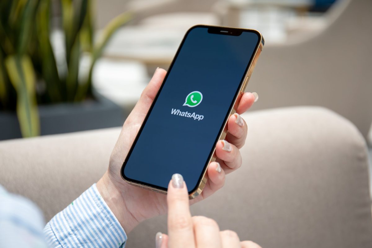 Person hält ein Smartphone, auf dem das WhatsApp-Symbol angezeigt wird.