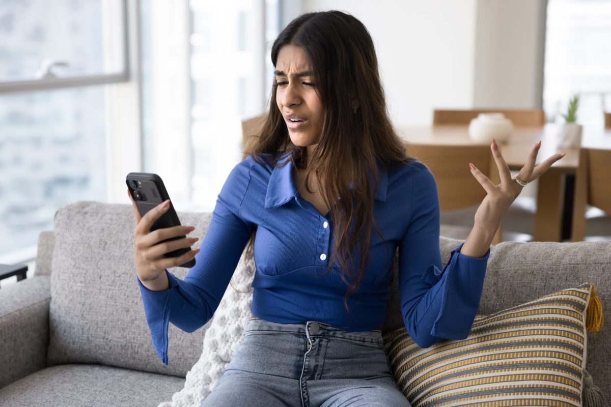 Frau hält Handy in der Hand und macht eine Geste der Unverständnis.